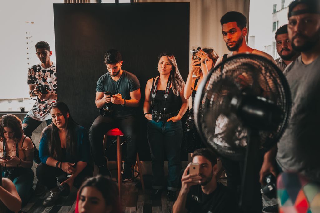 Group of young multiracial workers in casual clothes gathering together in modern studio during film making